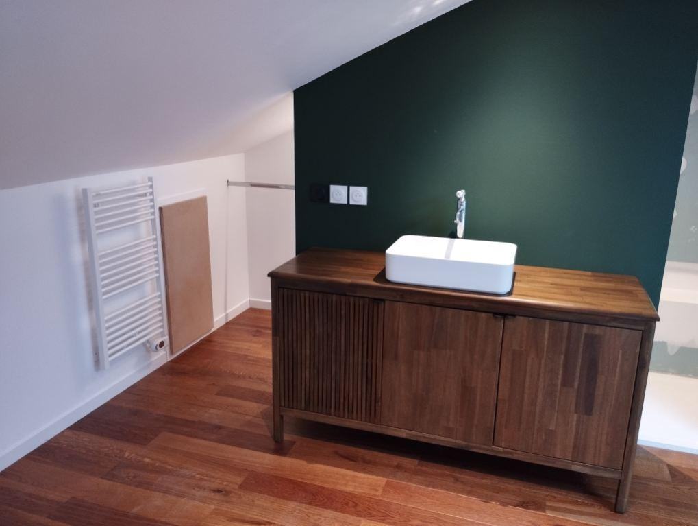 Vasque sur meuble en bois devant un mur vert