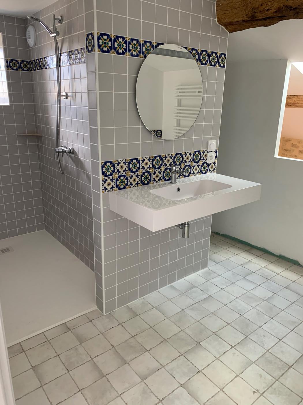 Salle de bain avec douche à l'italienne, vasque et frise de carreaux