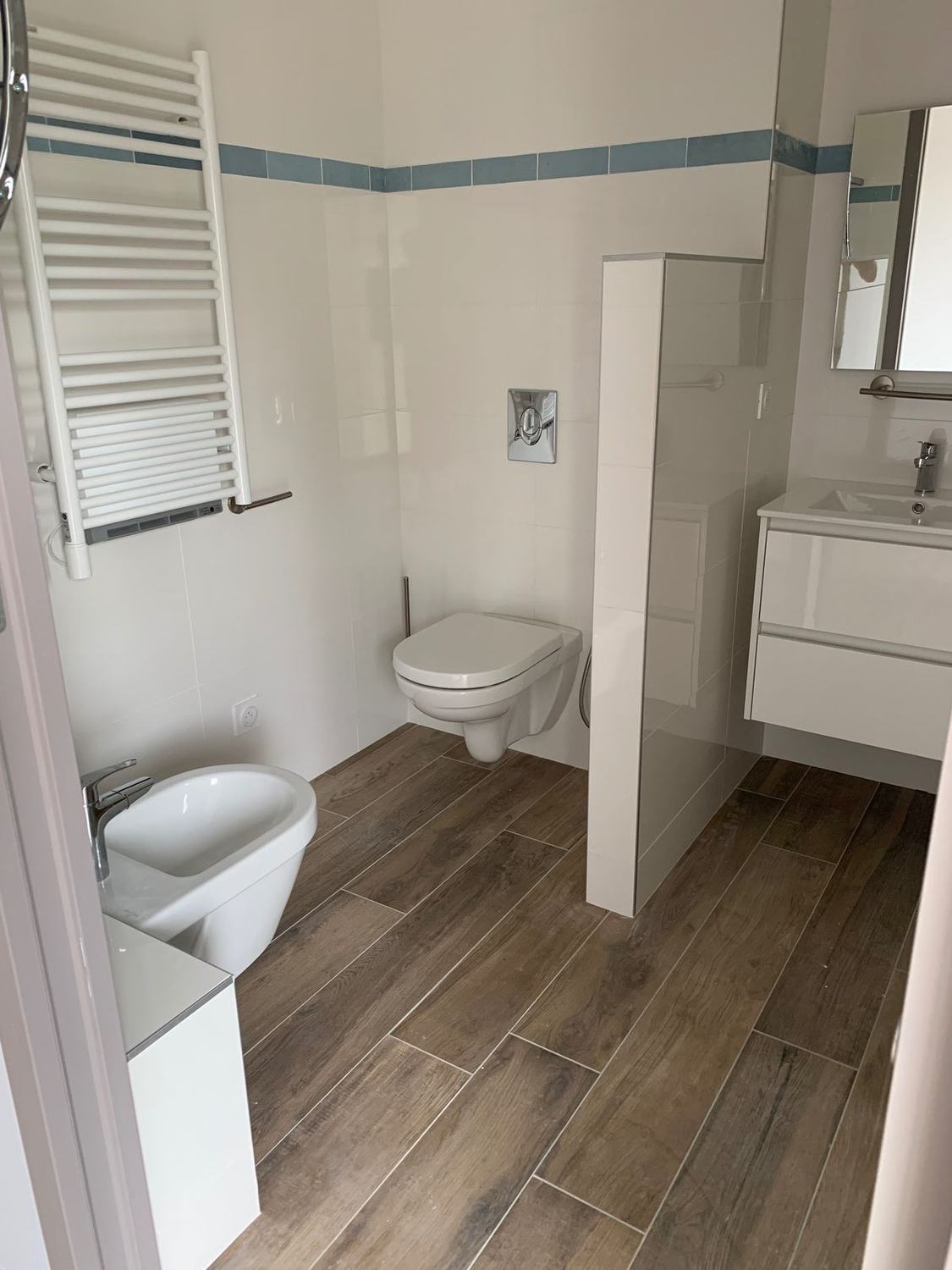 Salle de bain avec WC suspendu, sèche-serviettes et paroi de séparation
