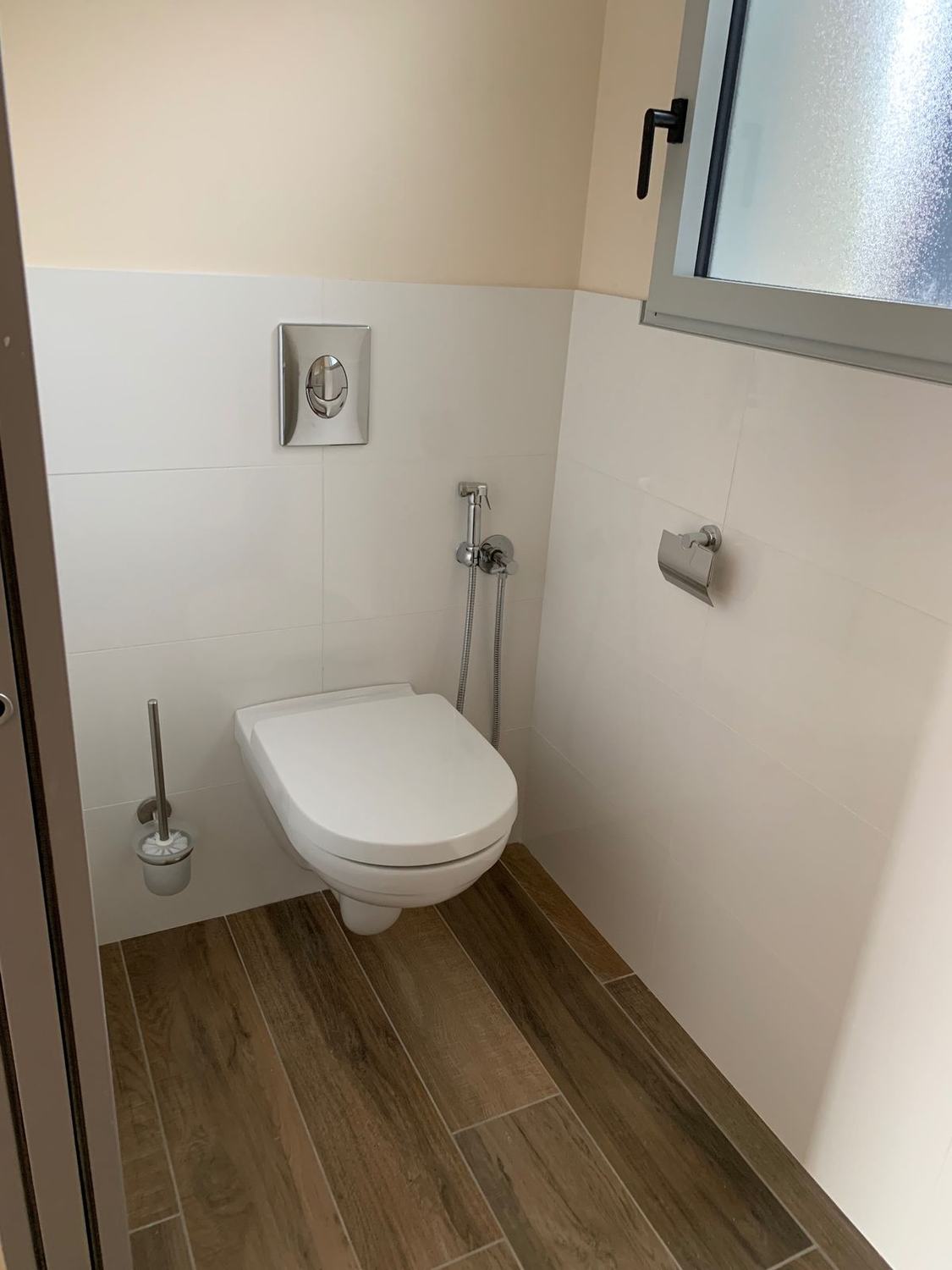 WC suspendu avec douchette et carrelage blanc
