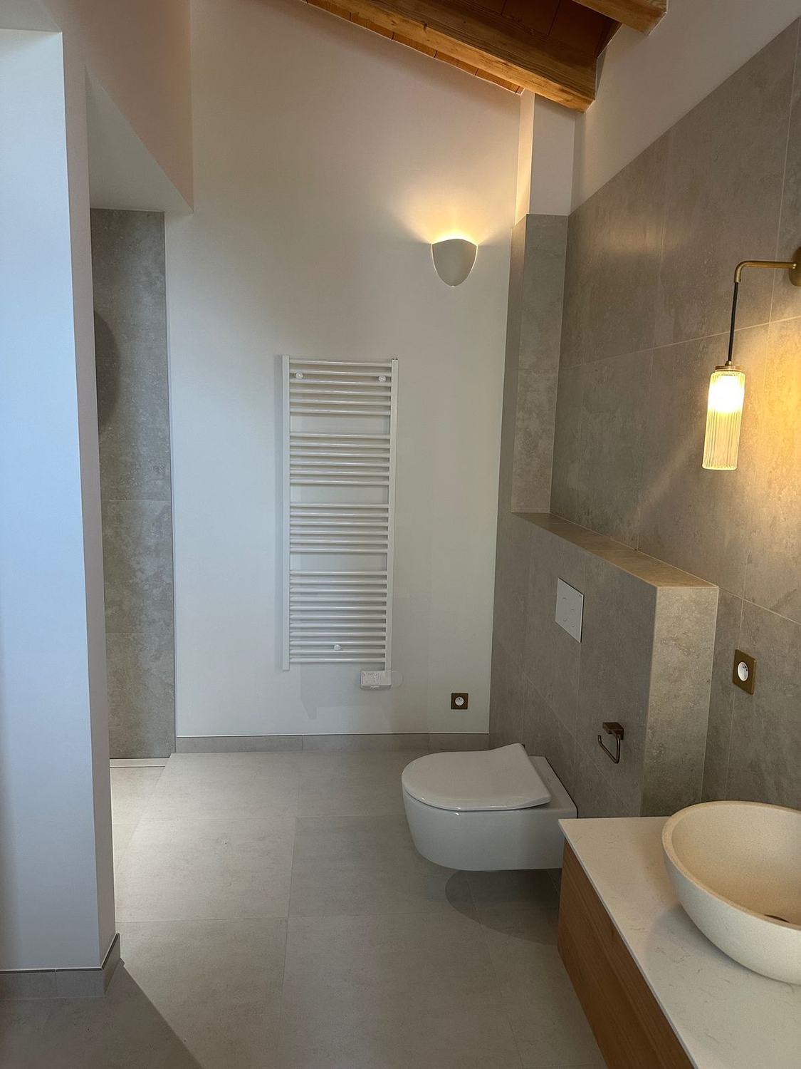 Salle de bain avec sèche-serviettes, applique et vasque sur meuble bois